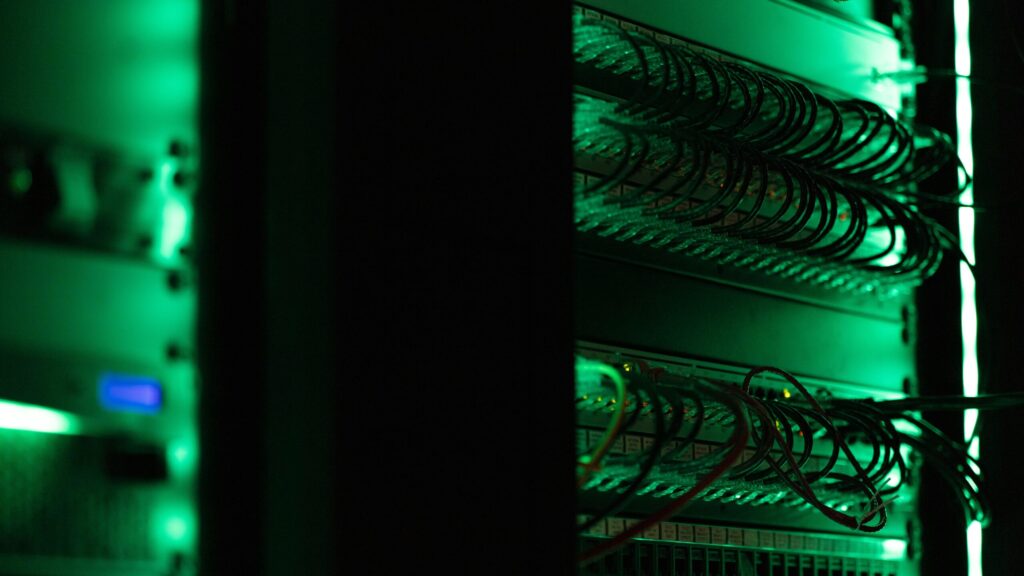 Stock photograph of a rack of server equipment in a dark room, used to illustrate an article about server log file analysis. It is not a photograph of a client server or of any real hosting environment.