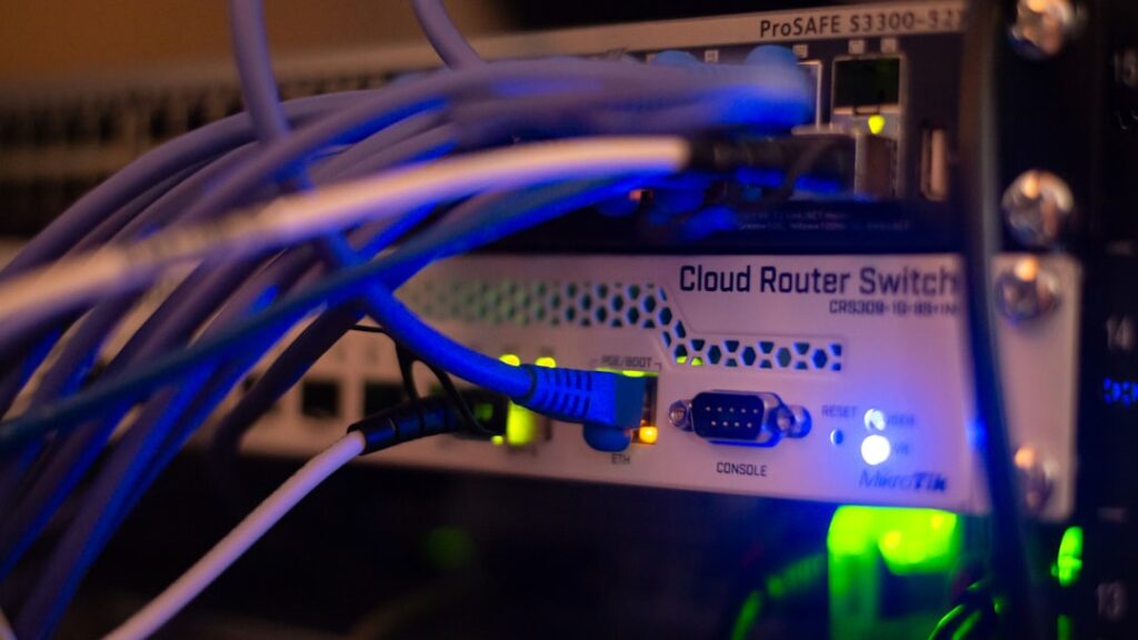 Stock photograph of rack-mounted networking equipment with ethernet cables plugged into its ports.