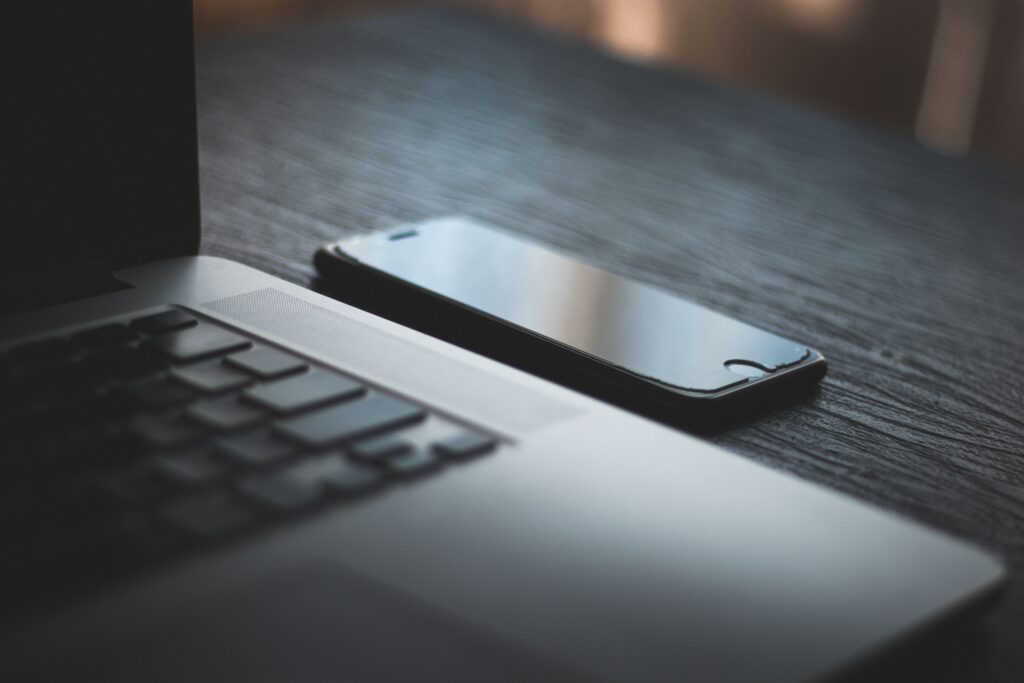 A laptop and a smartphone side by side on a wooden desk, a stock photograph from Pexels
