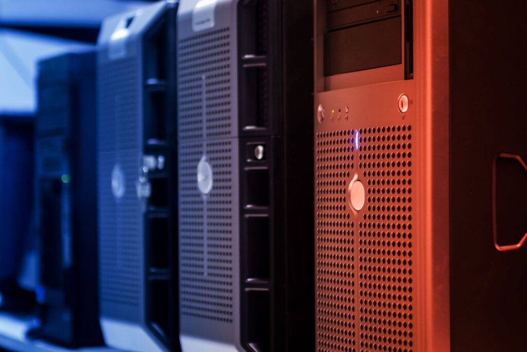 Stock photograph of tower servers in a data centre lit in blue and red. It is a generic illustration and not a photograph of any specific client server or hosting environment.