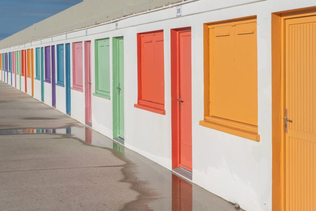 Stock photograph of a row of brightly painted doors side by side in sunlight, used to illustrate doorway pages
