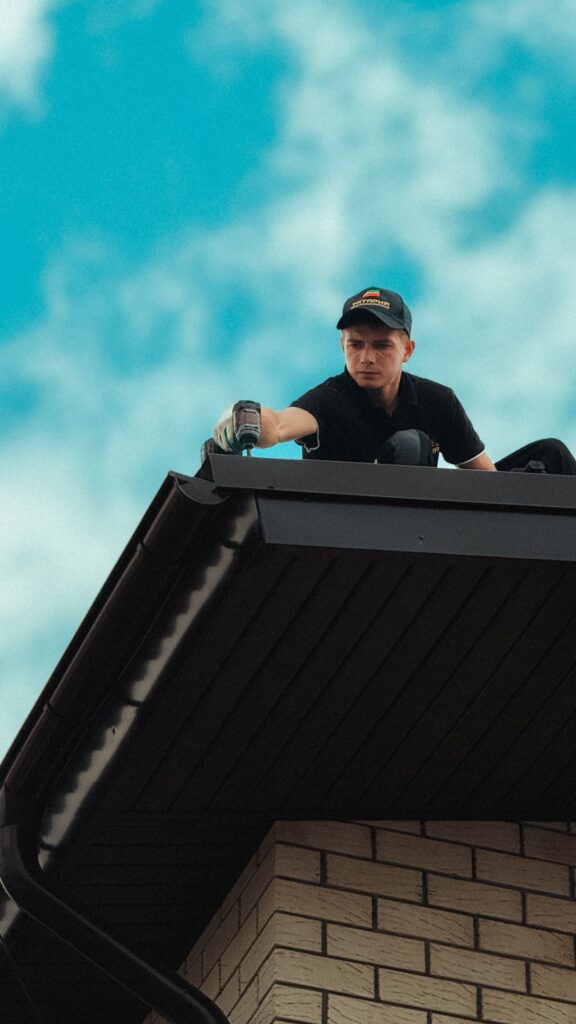 Stock photograph of a roofer working on a house roof under a blue sky. Illustrative only, not one of my clients.