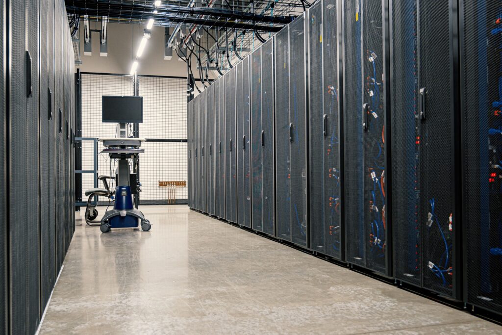 Stock photograph of a data centre corridor lined with server racks. It is a generic stock image and not a photograph of Google's infrastructure or any client system.