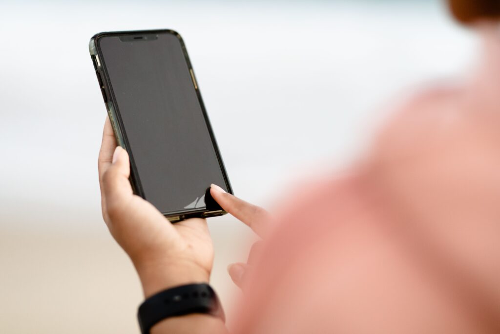 Stock photograph of a hand tapping a smartphone touchscreen outdoors. It is a generic illustration of mobile use and not a screenshot of any website or Search Console report.