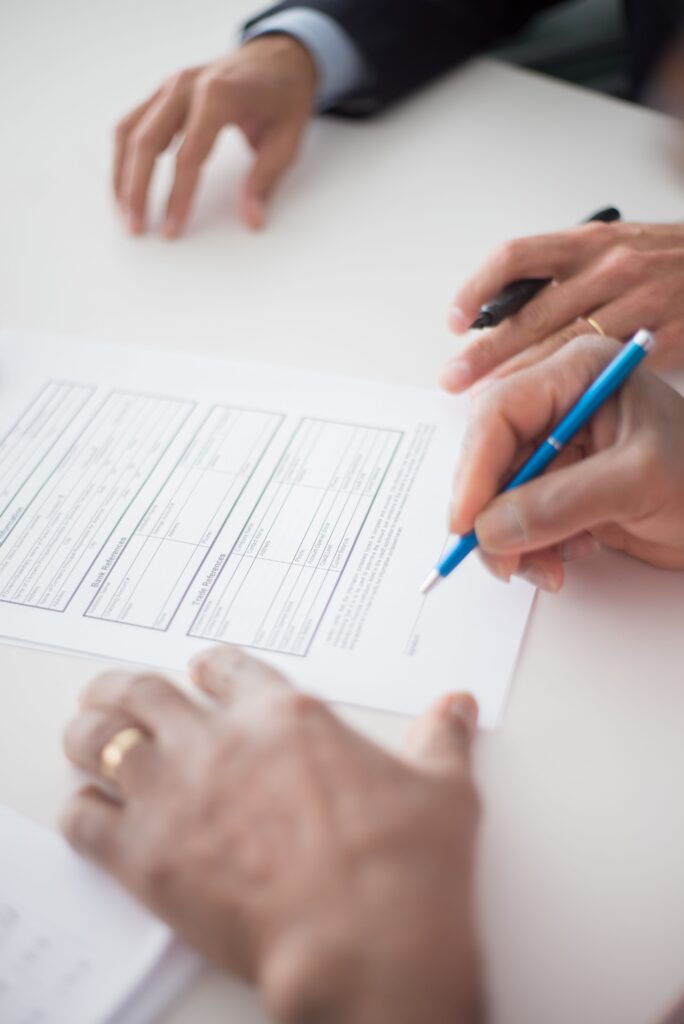 Stock photograph of hands signing a business document with a pen on a white desk. Not a real SEO proposal or client.