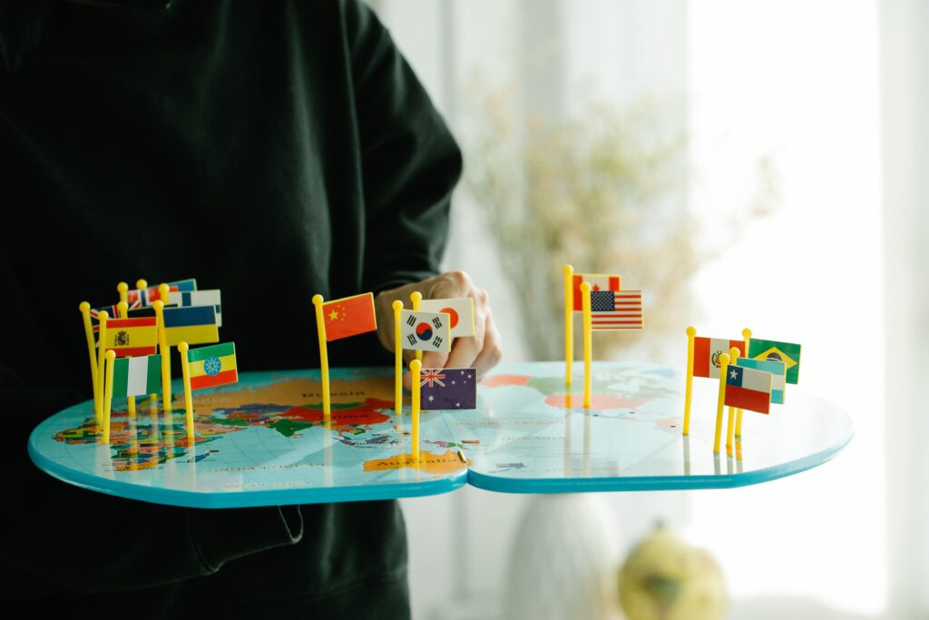 A printed world map with small national flags standing on several countries, photographed from above.