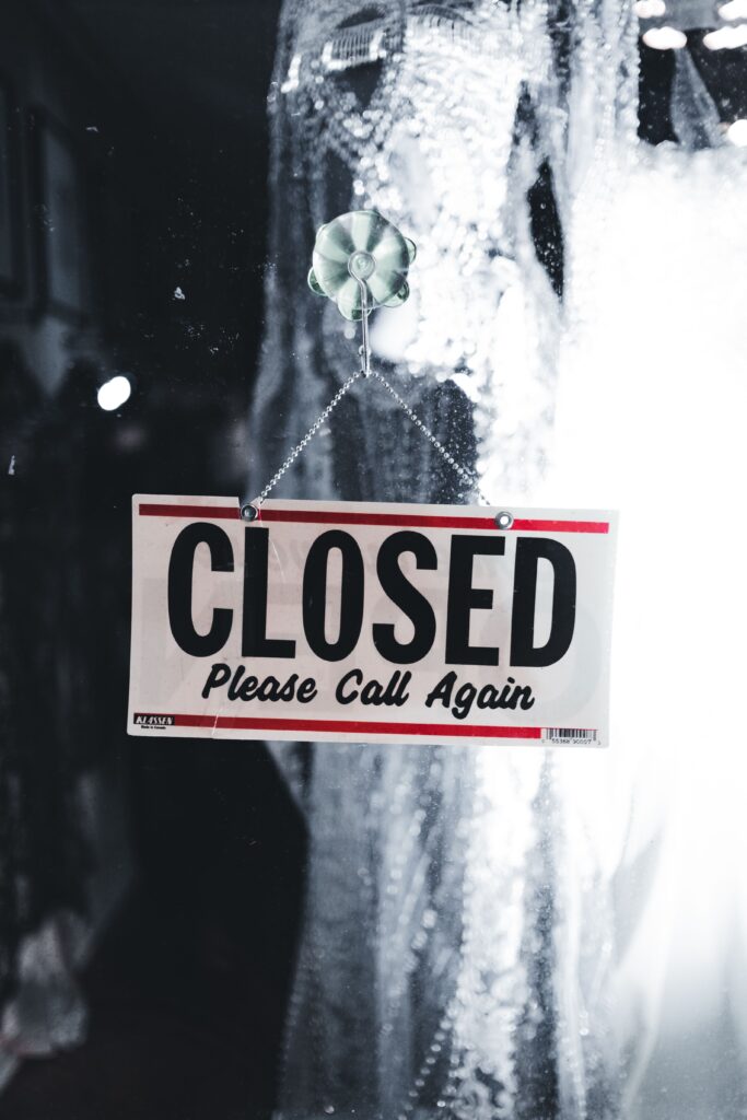 Stock photo of a Closed sign hanging on a glass shop door. Not a real client business.